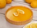 Una deliziosa crostata al limone, con la sua crema gialla brillante e decorata con spicchi di limone fresco.