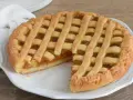 Crostata con marmellata, un classico della crostata ricetta tradizionale, servita su un piatto bianco con un tovagliolo di lino.