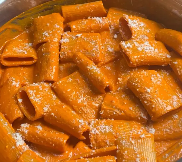 Rigatoni conditi con una cremosa salsa all'nduja, cosparsi di formaggio grattugiato. Un piatto invitante e saporito.