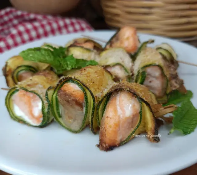 Deliziosi involtini di zucchine con salmone e formaggio, guarniti con menta fresca.